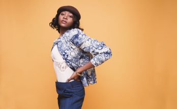 Portrait of a young woman in stylish clothing posing against a yellow background. — Using Stylistic Jewellery to brighten Bea