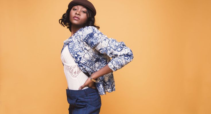 Portrait of a young woman in stylish clothing posing against a yellow background. — Using Stylistic Jewellery to brighten Bea