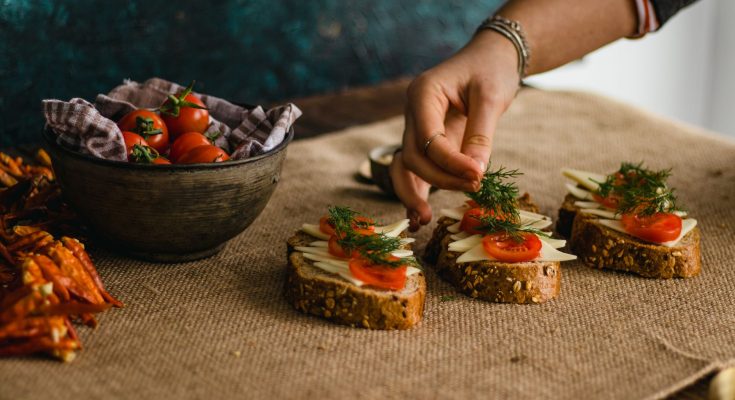 Close-up of a hand preparing artisan multigrain sandwiches with cheese and tomatoes. — What Food Enables You To Fat: How you