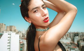 A young fashion model poses confidently on a city rooftop with a striking urban skyline. — Wood Furniture May Bring An All Na